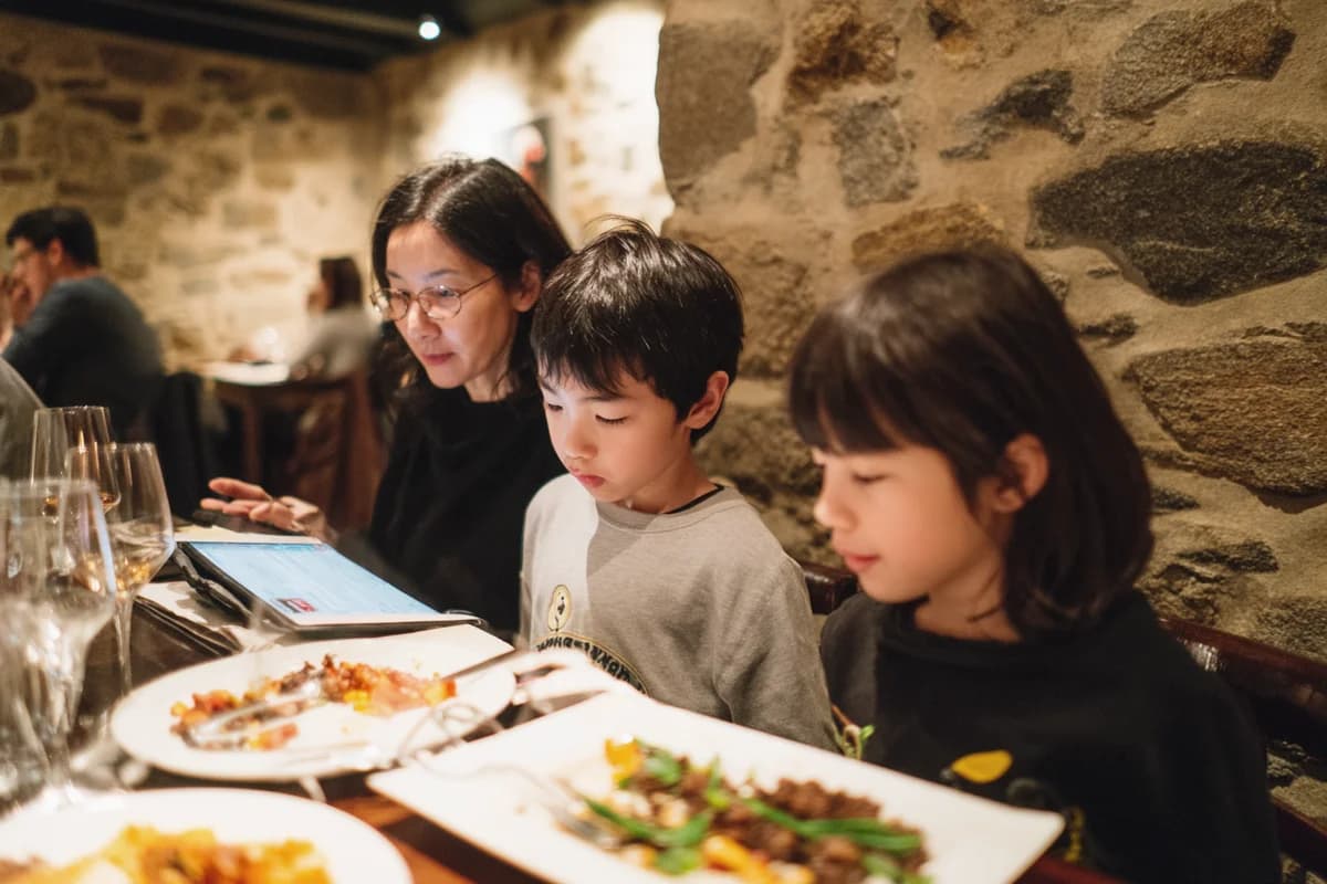 Famille consultant le menu digital avec filtrage allergènes dans un restaurant basque